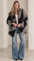 Front view of model wearing black and grey chevron shaggy faux fur coat with flare jeans