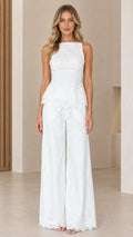 Front view of model wearing white embroidered peplum top and wide leg pants set