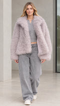 Front view of model wearing dusty lilac textured shaggy faux fur jacket with wide-leg jeans