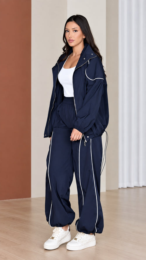 Front view of woman wearing navy blue 2-piece windbreaker tracksuit set with white contrast piping
