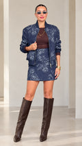 Front full-length view of model wearing Navy Blue paisley jacquard bomber jacket and skirt set with tall boots