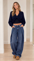 Front view of model wearing Navy Blue twist-front cropped sweater with wide-leg jeans