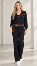 Front full view of woman wearing black zip-up tracksuit set with orange striped trim