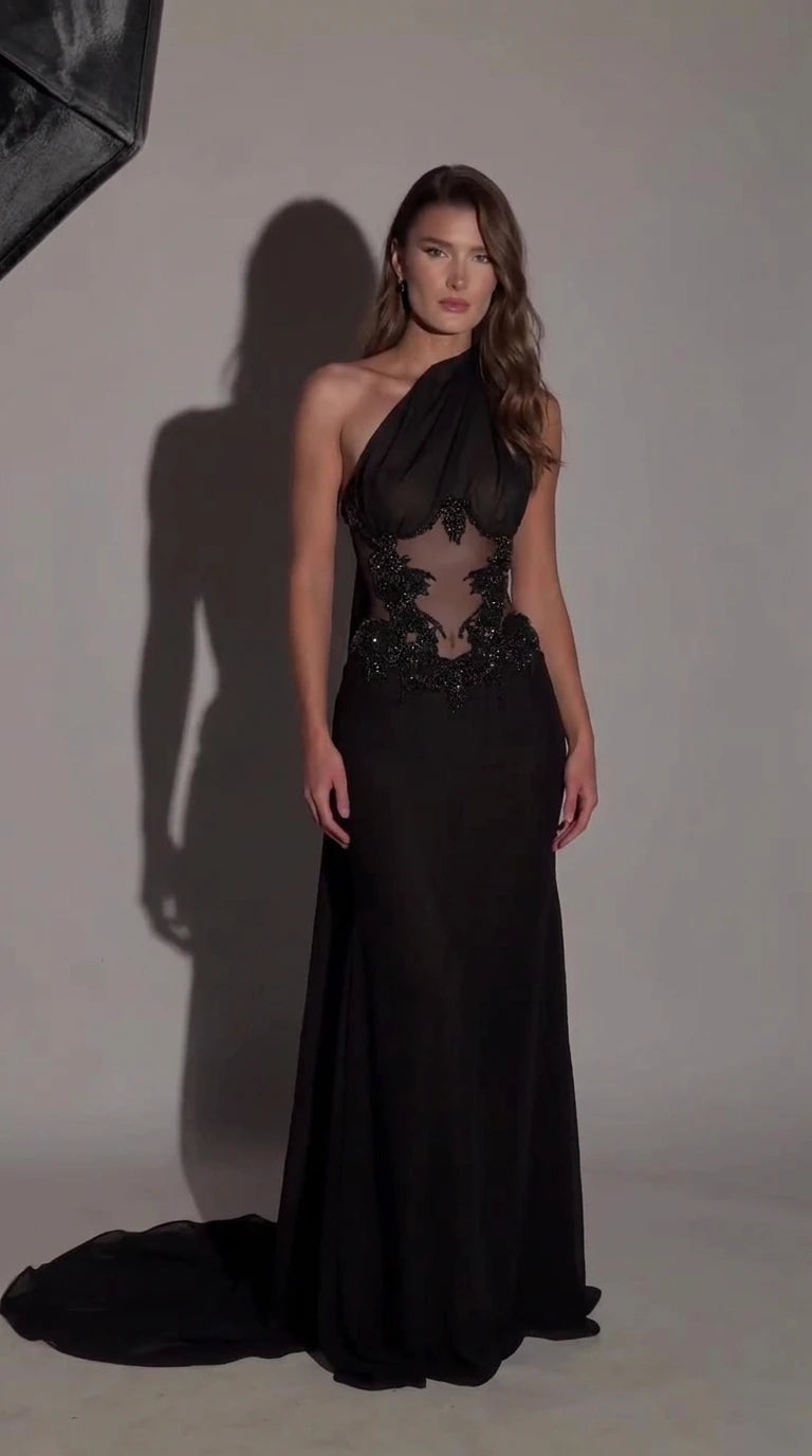 Front view of black one-shoulder evening gown with beaded sheer illusion waist and train