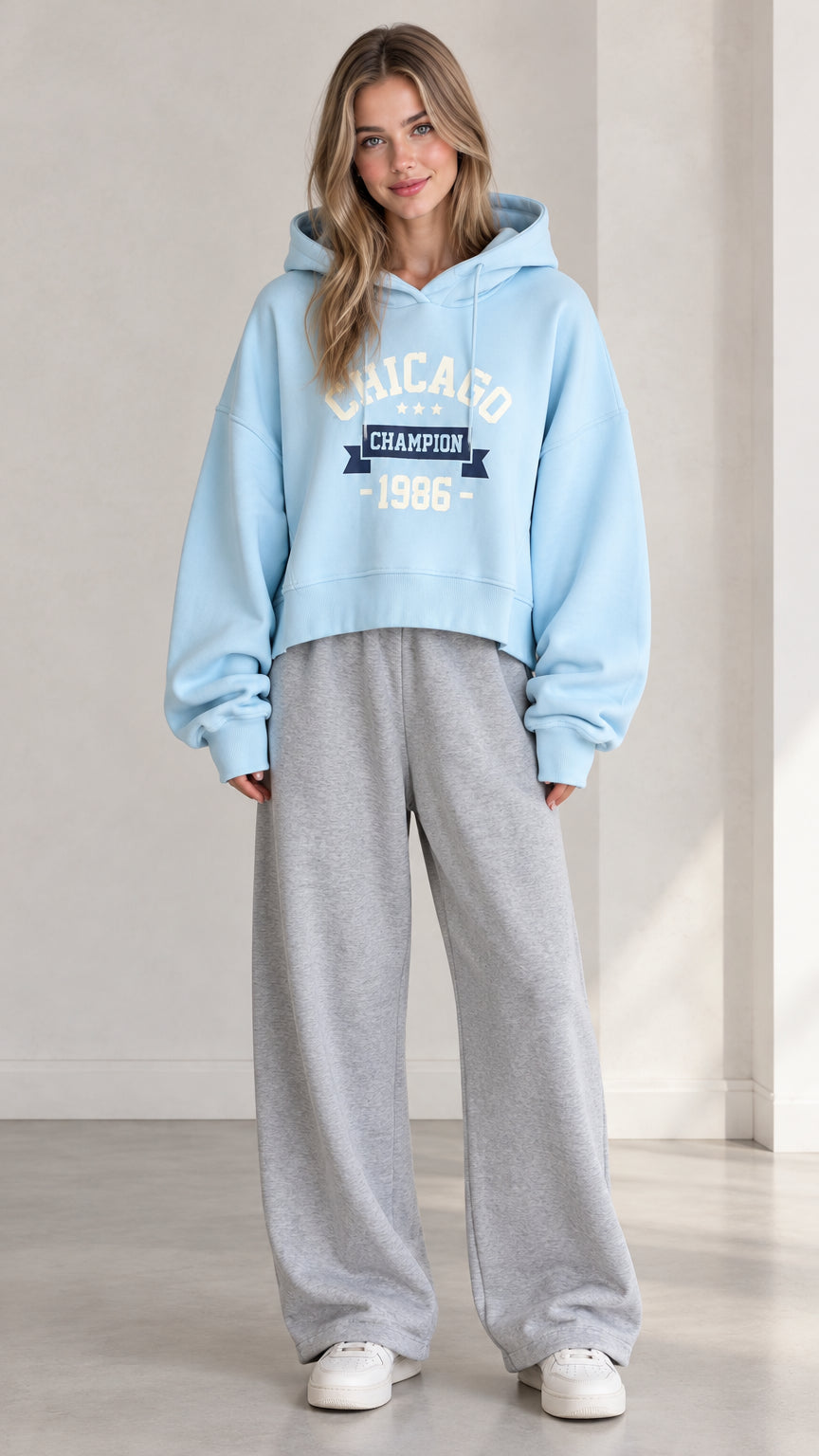 Front view of woman wearing Light Blue Chicago graphic cropped hoodie with gray sweatpants