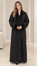 Front full-length view of model wearing black open-front abaya coat with faux fur collar and sequined sleeves