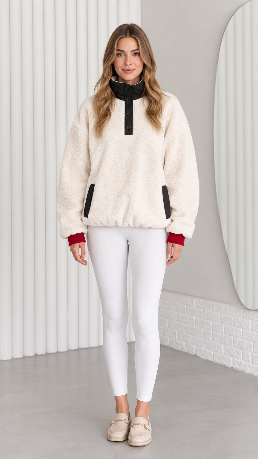 Front view of model wearing cream sherpa fleece pullover with black mock neck and white leggings