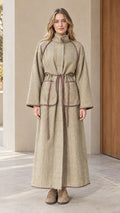 Front full-length view of woman wearing sage green herringbone piped maxi coat