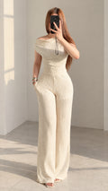 Front view of woman wearing cream textured off-shoulder top and matching wide-leg pants
