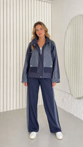 Front full view of woman wearing navy blue textured contrast zip-up jacket and wide-leg pants set