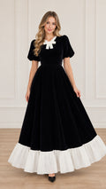 Front view of black velvet maxi dress with white bow collar and white ruffle hem