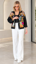 Front view of model wearing black floral embroidered sheer mesh shirt jacket with white wide-leg trousers