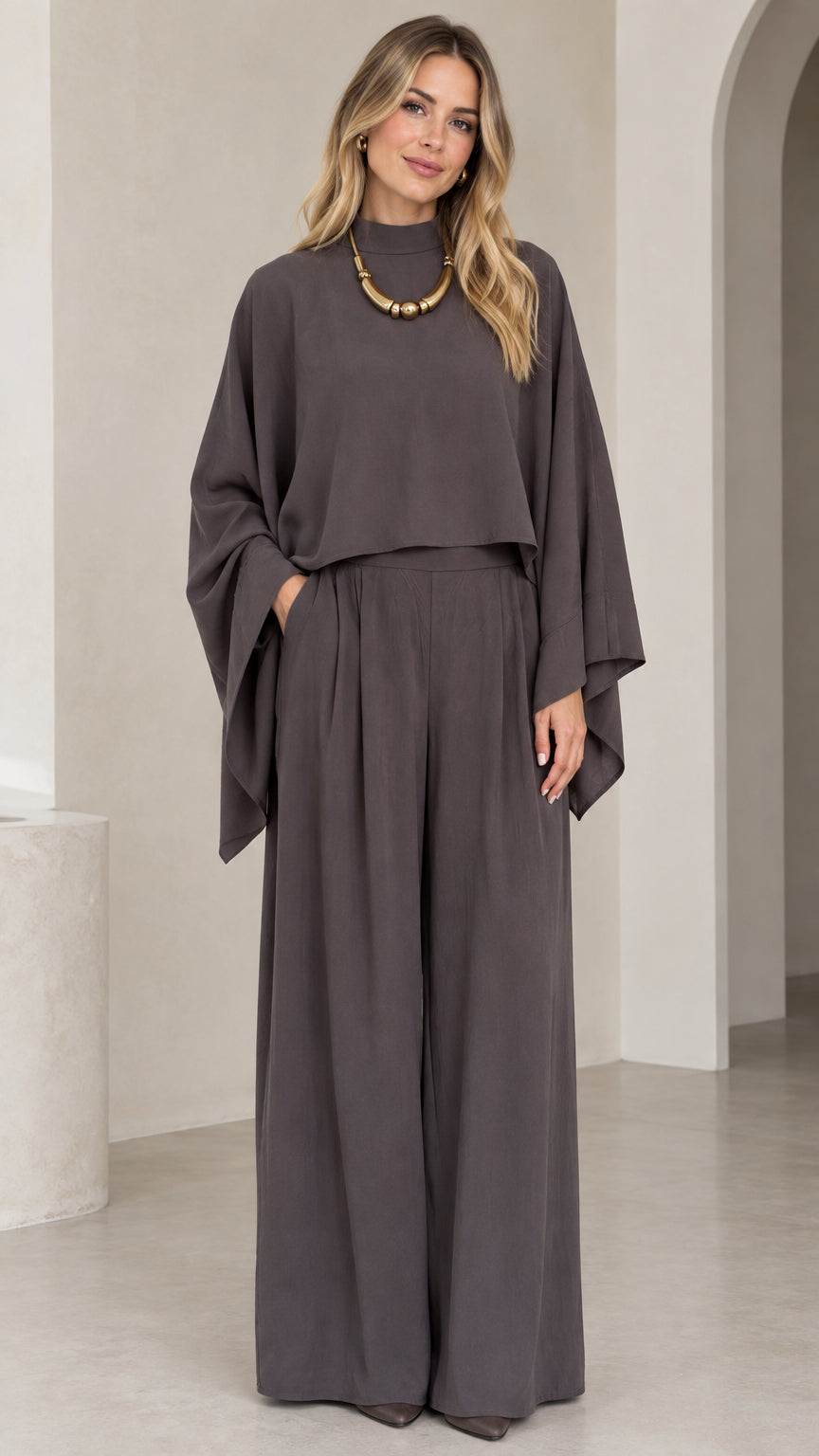 Front full-length view of woman wearing charcoal grey mock neck cape top and pleated wide leg pants set