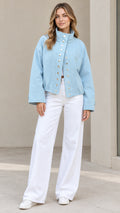 Front full-length view of woman wearing Light Blue stand collar snap jacket and white wide-leg trousers