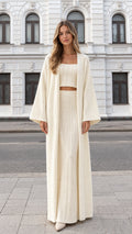 Front full-length view of woman wearing cream 3-piece cable knit duster, crop top, and skirt set
