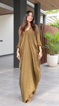 Front view of model wearing a textured gold V-neck maxi kaftan dress with batwing sleeves