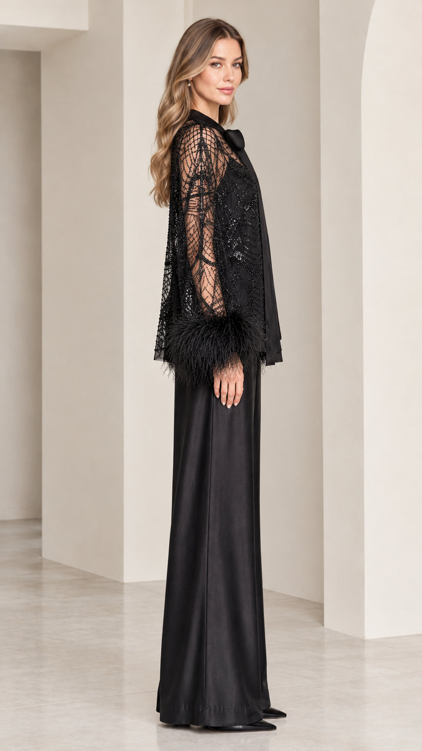 Side view of model in black embellished evening pant set with feather cuffs
