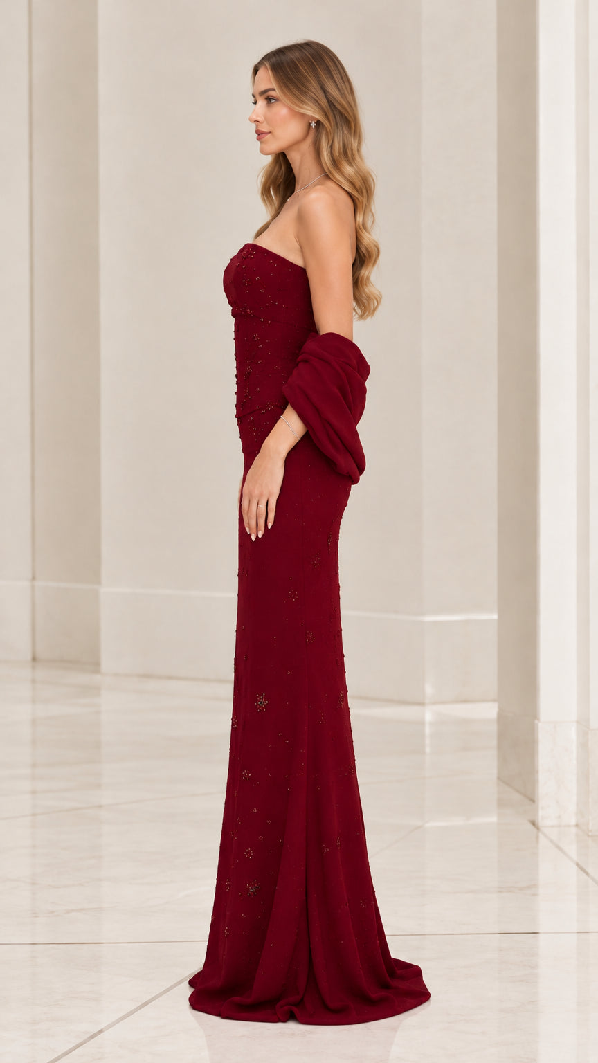 Side profile view of burgundy strapless formal gown showing floor-length column cut