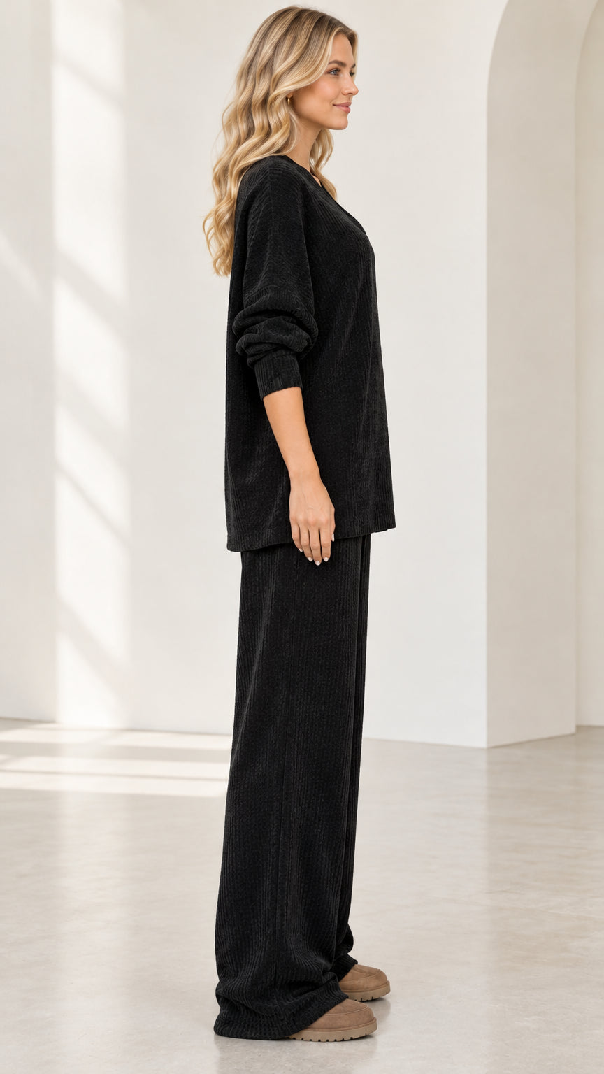 Side profile view of woman wearing black textured knit loungewear two piece set