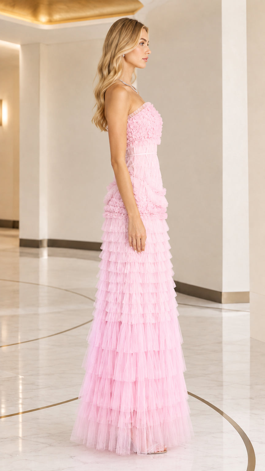 Side view of woman posing in pink strapless tiered ruffle tulle formal gown