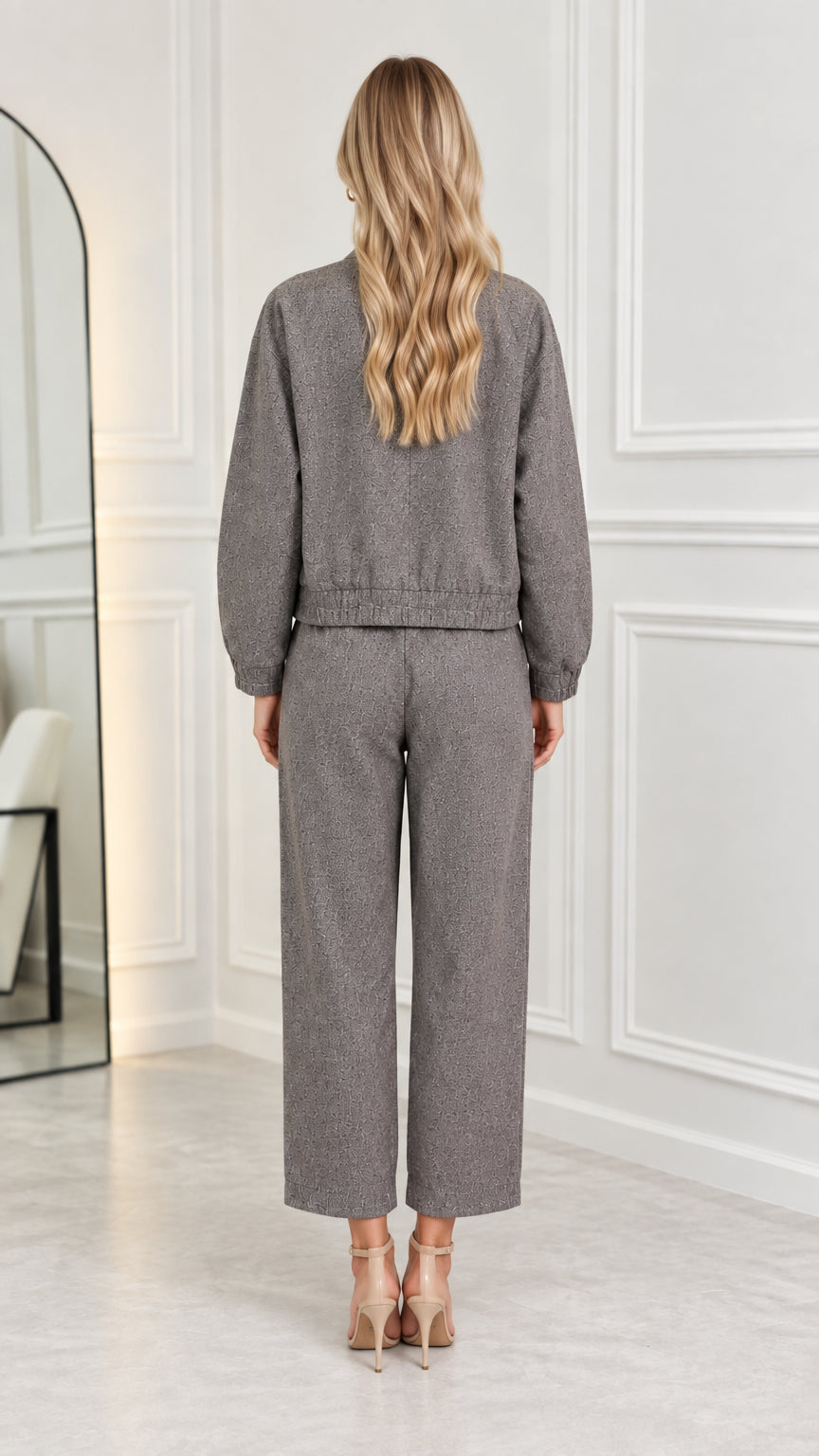 Back view of model wearing grey two-piece bomber jacket and straight trousers set