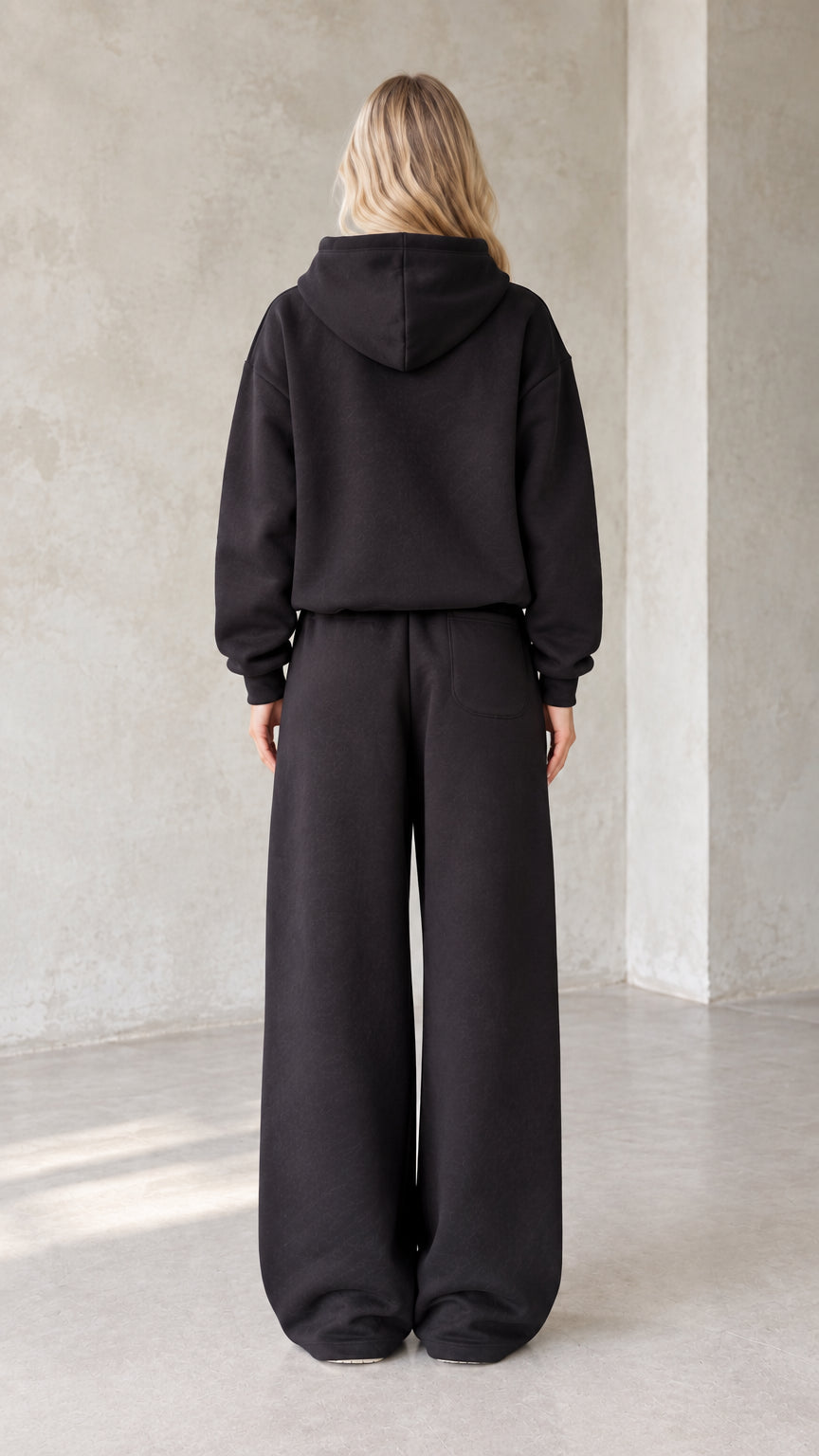 Back view of woman wearing black oversized hoodie and matching sweatpants