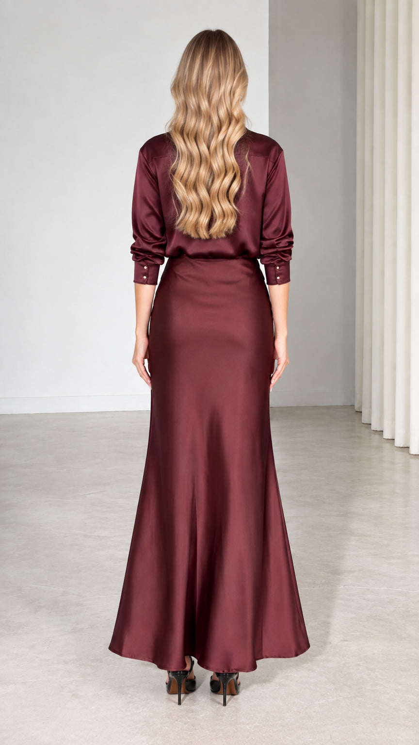 Back view of model showing burgundy satin long-sleeve shirt and maxi skirt