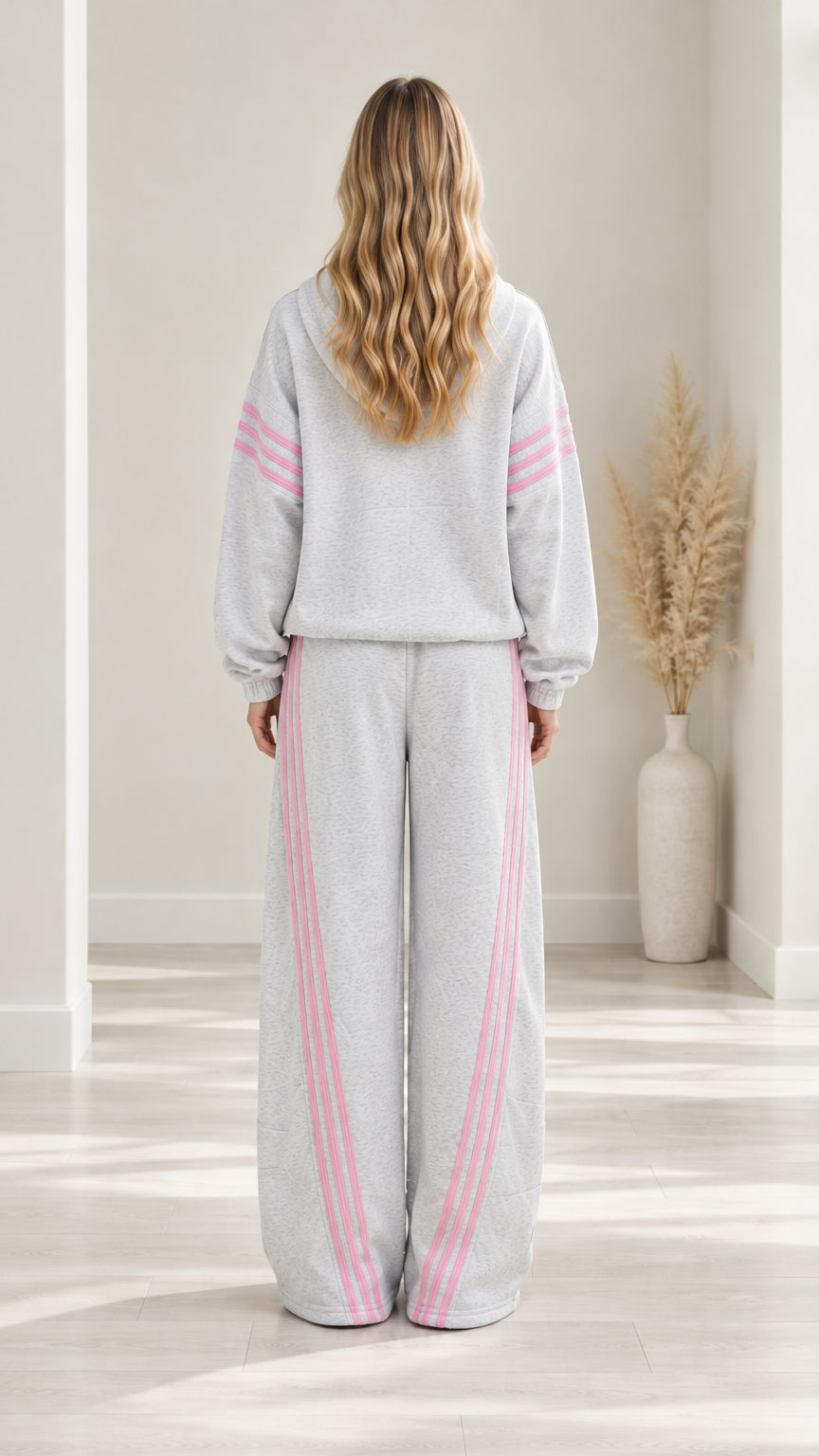 Back view of woman wearing Heather Grey lounge tracksuit set with pink sleeve and leg stripes