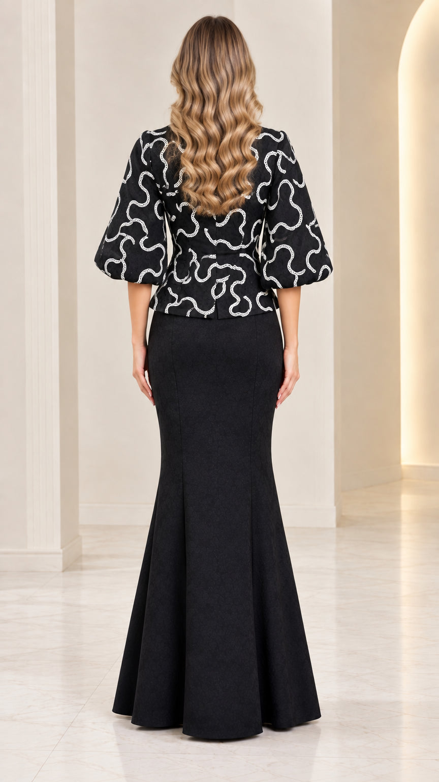 Back view of model wearing black lantern sleeve peplum top and mermaid skirt