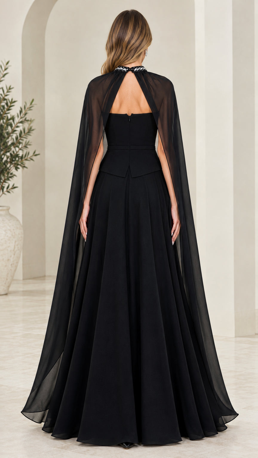 Back view of black formal maxi dress displaying keyhole back detail and flowing cape