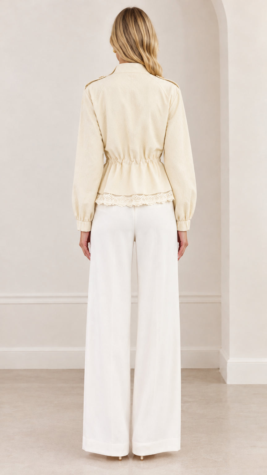 Back view of cream cinched-waist jacket showing storm flap and peplum silhouette