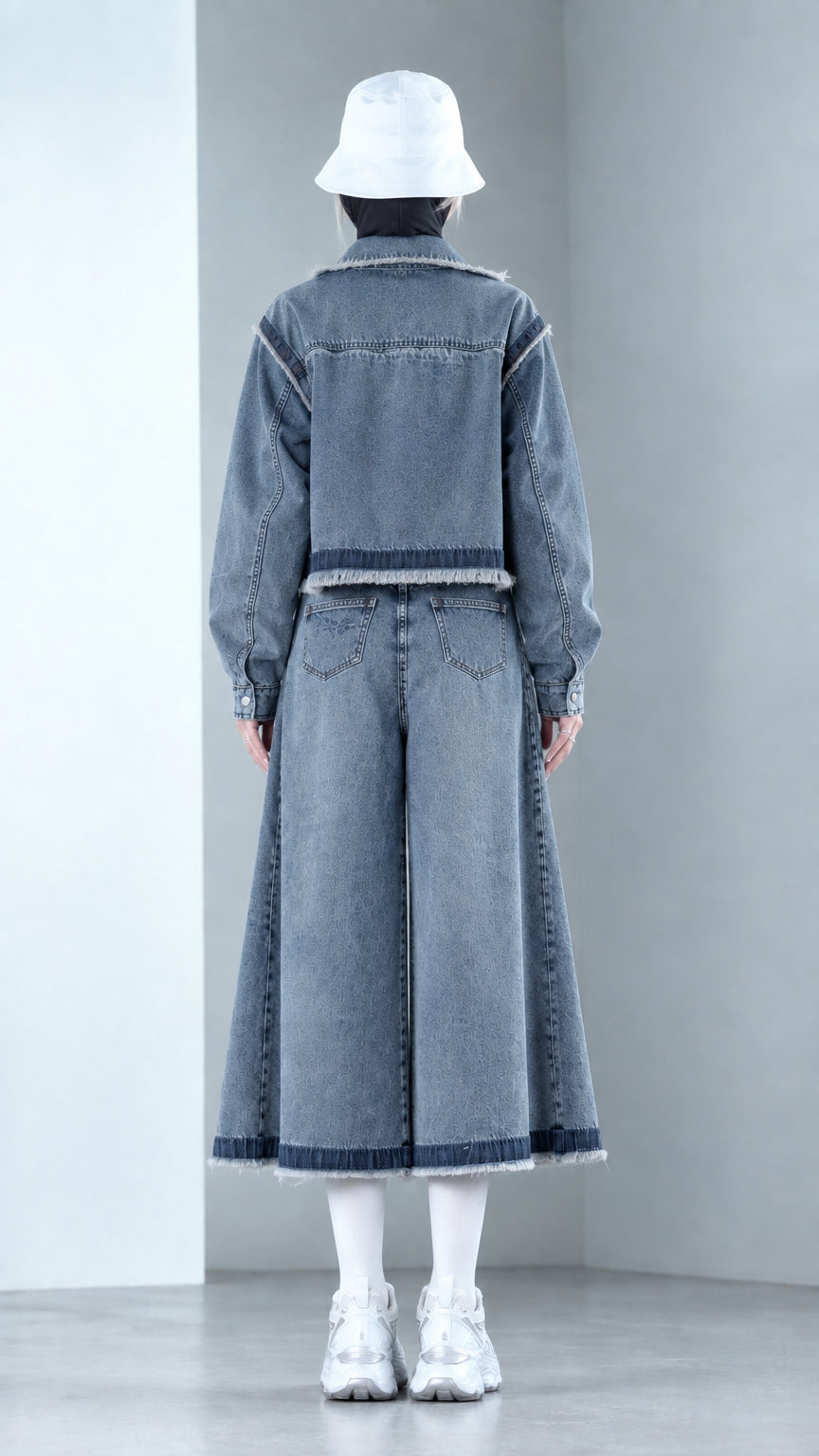 Back view of model wearing Denim Blue cropped denim jacket and wide-leg flared pants