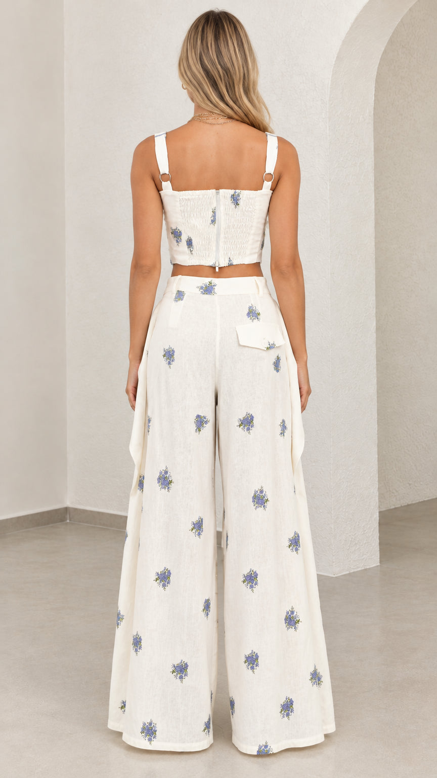Back view of model wearing white floral embroidered bustier top and wide leg pants