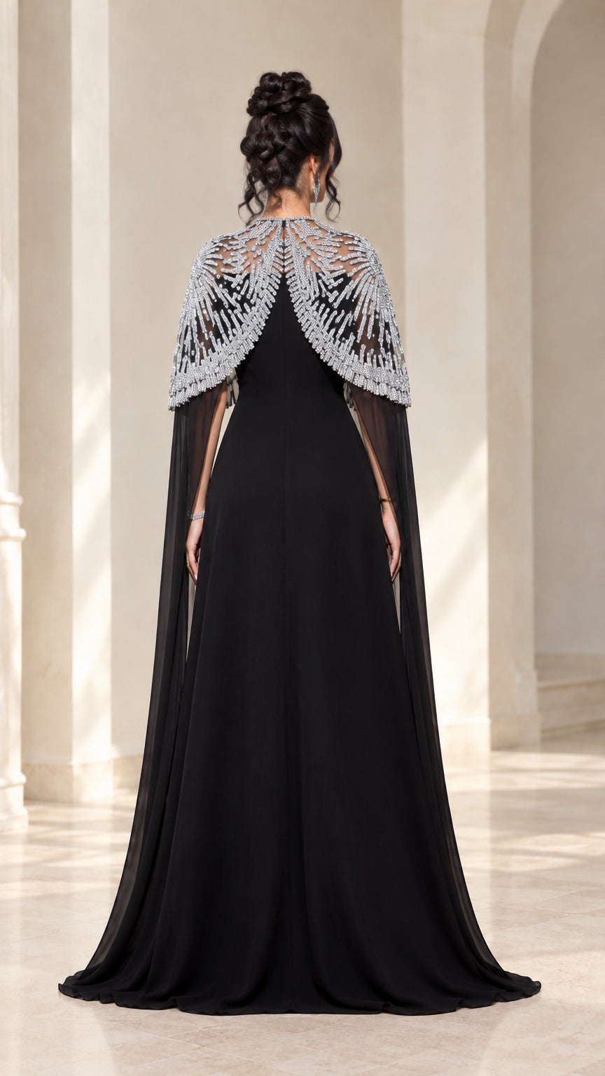 Back view of black evening gown featuring flowing sheer embellished cape