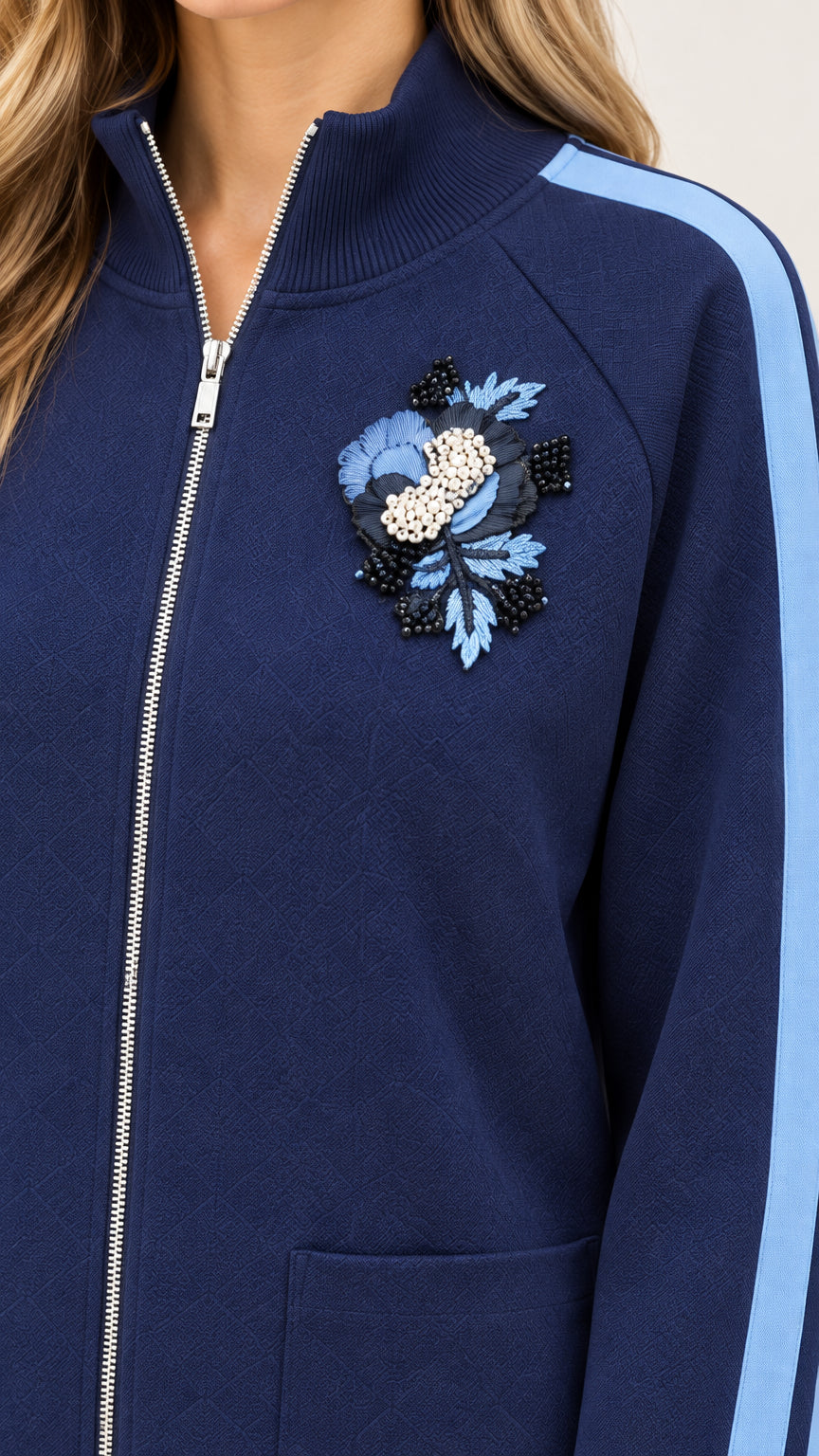 Close-up detail of navy blue jacket collar, front zipper, and beaded 3D floral appliqué on chest