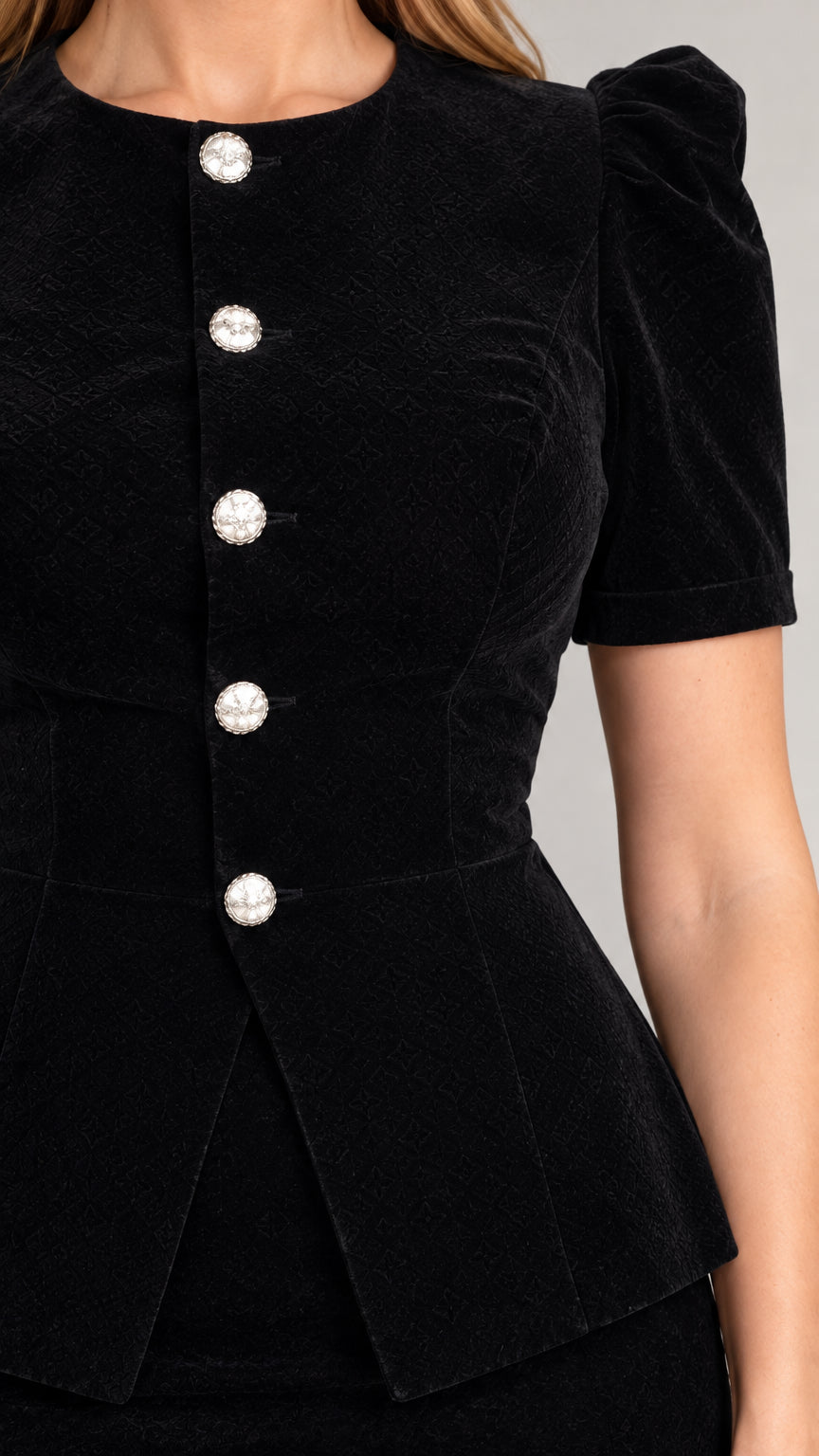 Close-up detail of textured black fabric and decorative faux-pearl buttons