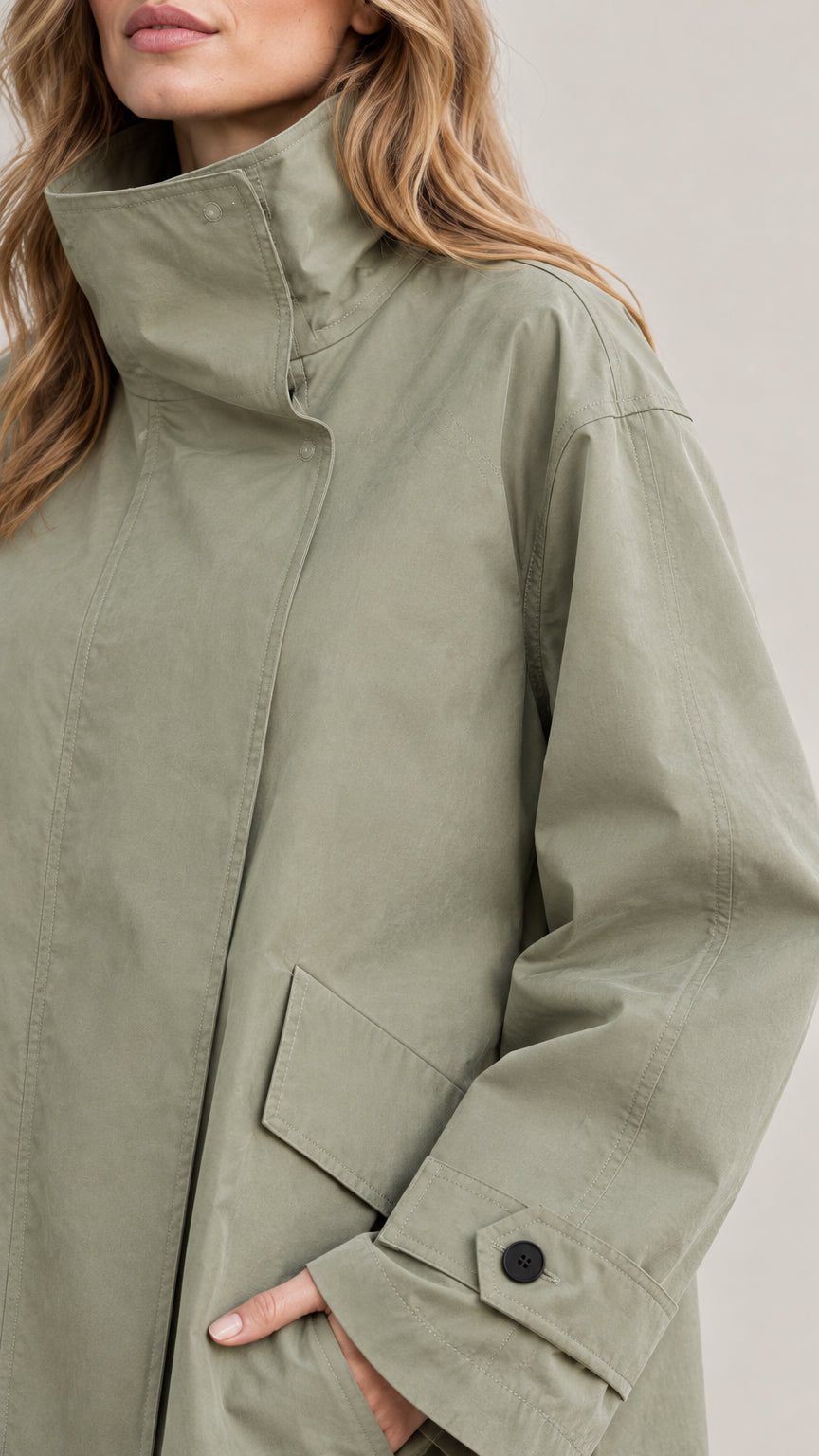 Close-up detail of high funnel collar, concealed placket, and flap pocket on Sage Green jacket