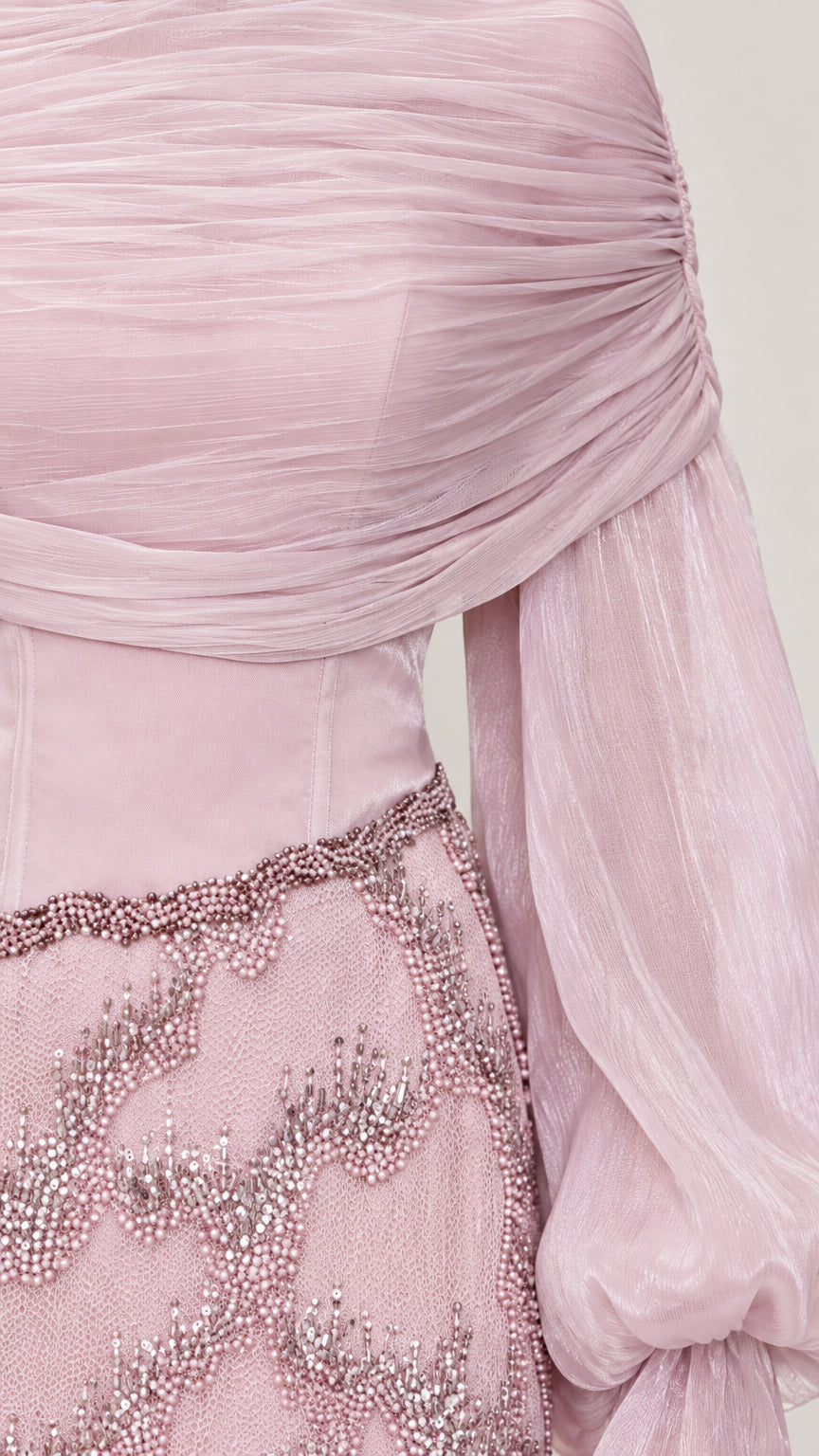 Close-up detail of pleated drape neckline and intricate beadwork on skirt waistband