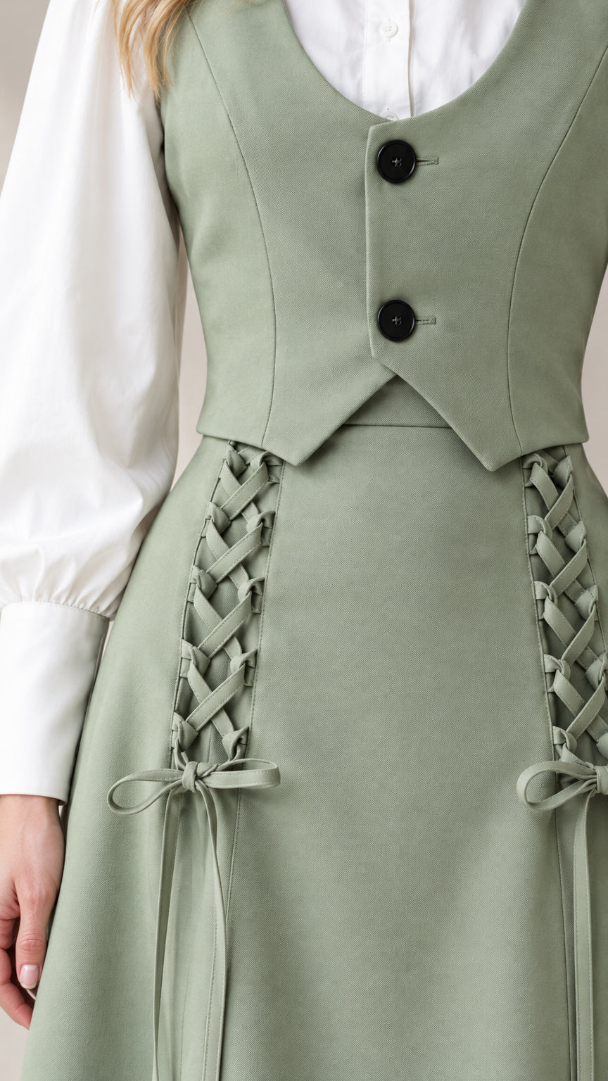 Close-up detail of sage green vest buttons and skirt side corset lacing