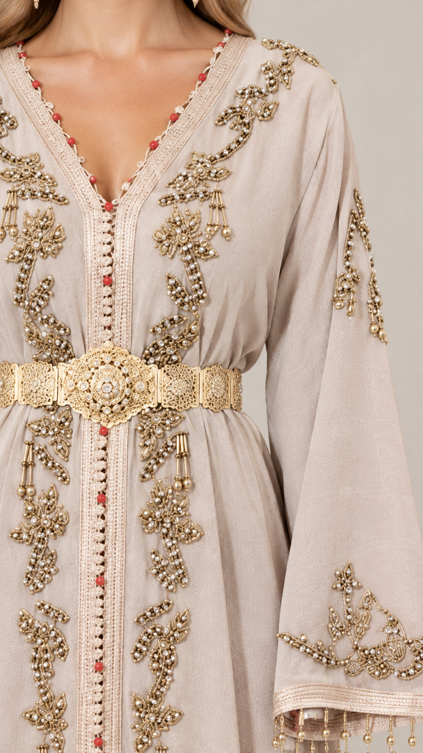 Close-up detail of gold embroidery and metallic waist belt on beige caftan