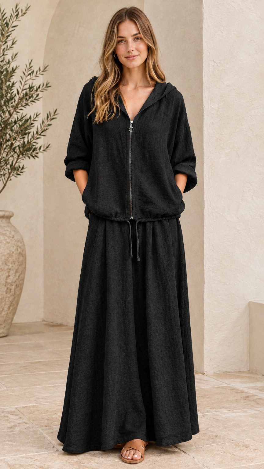 Front view of woman wearing black hooded zip-up top and maxi skirt set