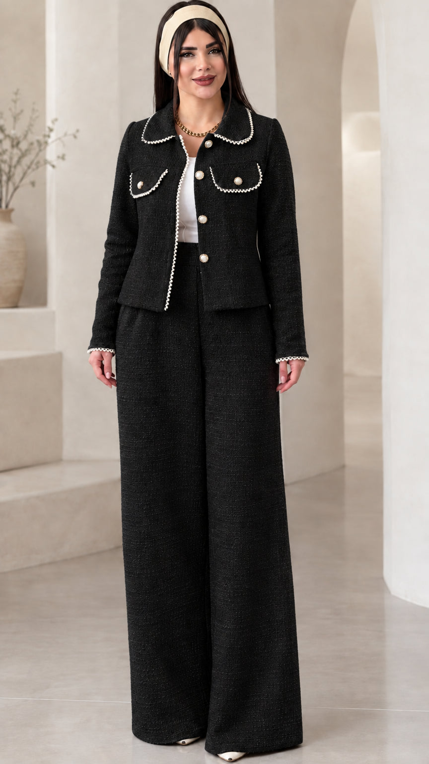 Front view of model wearing the black pearl-trimmed tweed jacket and wide-leg trousers set