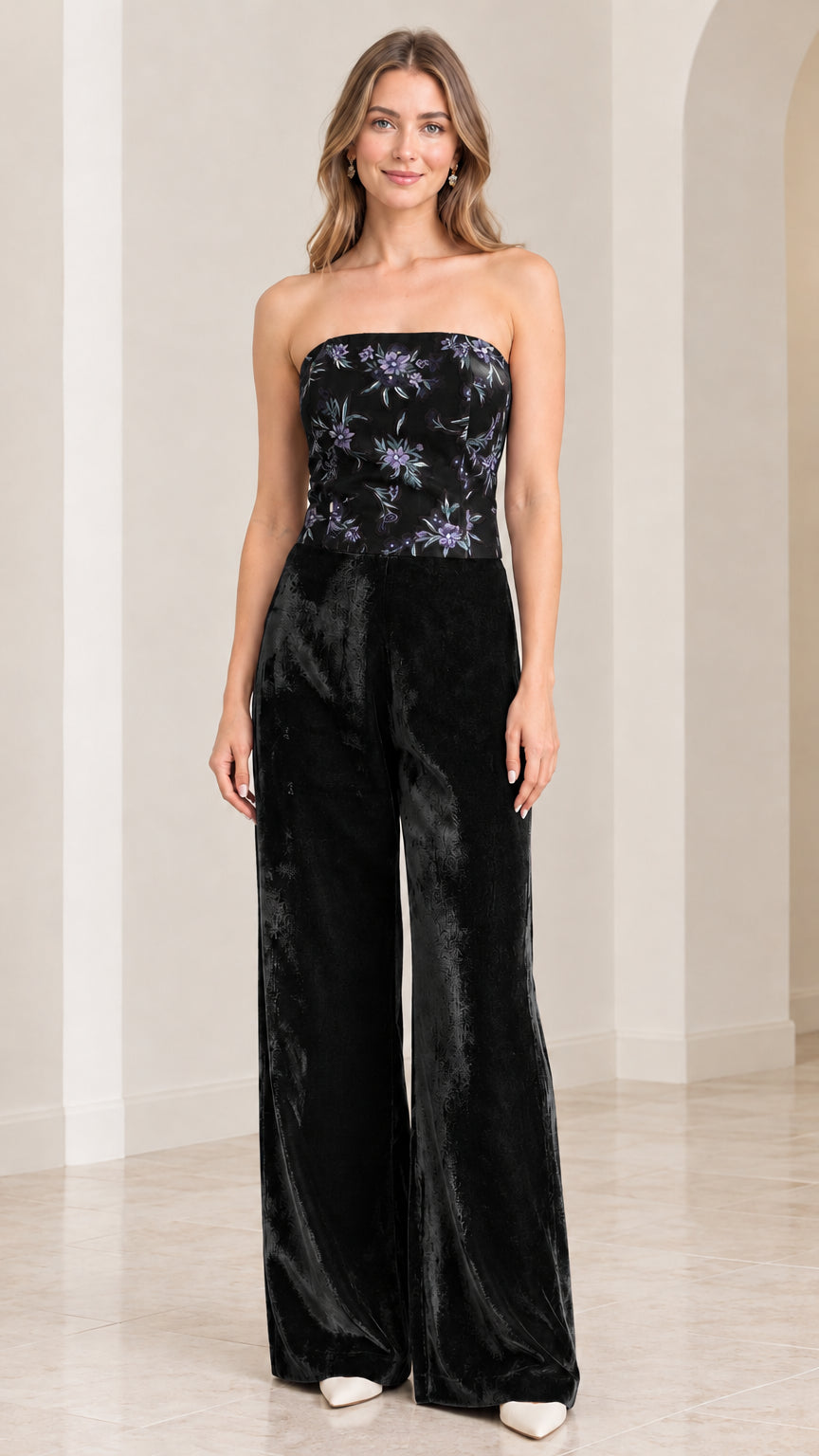 Front view of woman wearing strapless black floral velvet wide leg jumpsuit