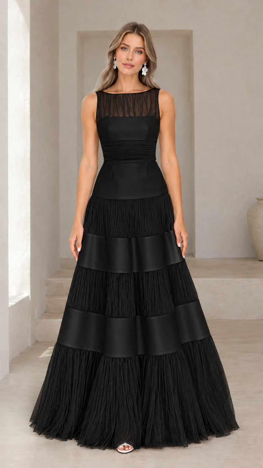 Front view of model wearing black sleeveless tiered tulle and satin gown
