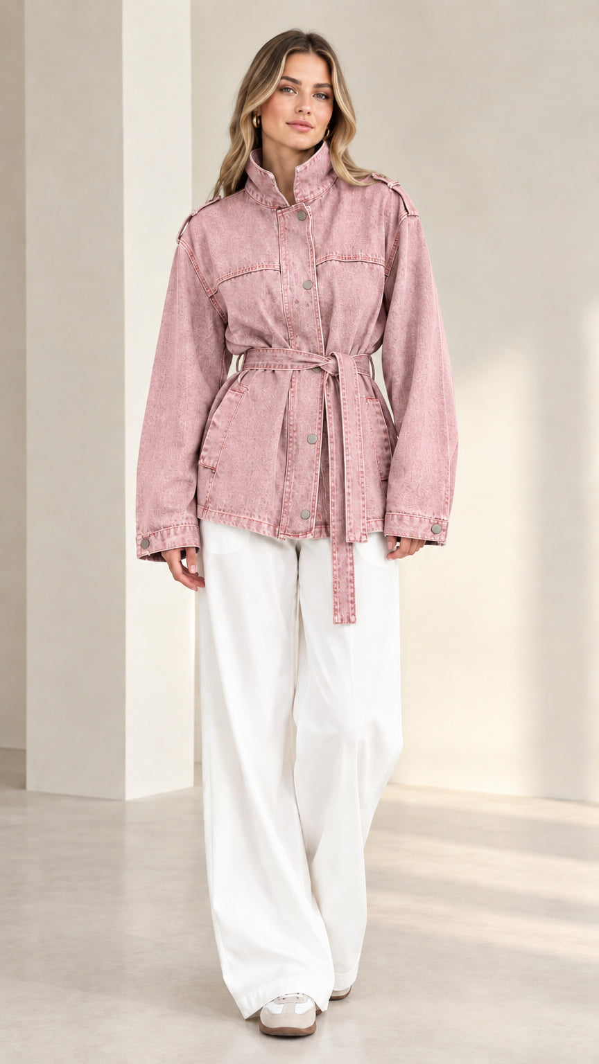 Front view of model wearing dusty pink belted denim jacket with white wide-leg trousers