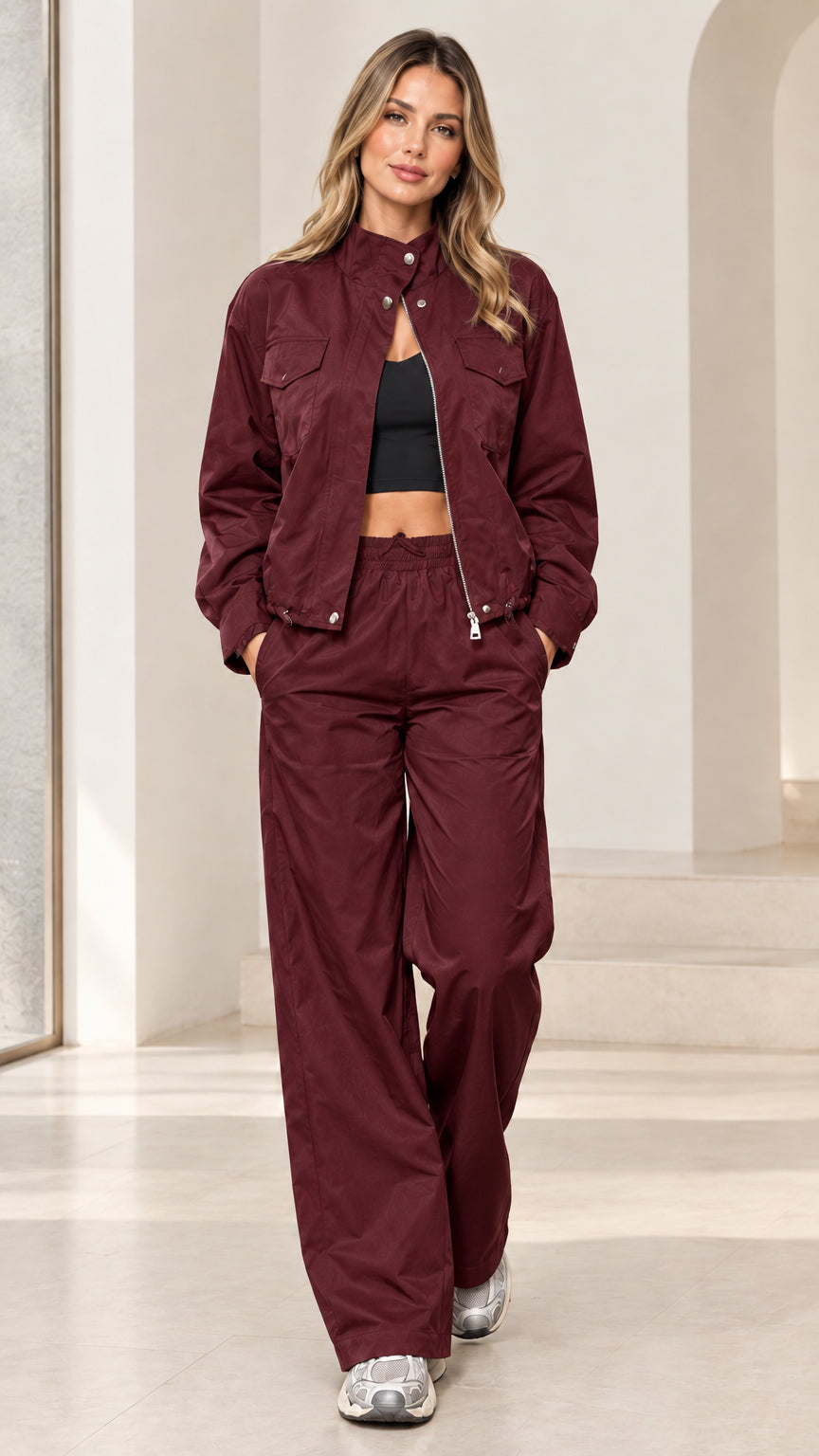 Full-length studio shot of woman wearing burgundy wine zip-up windbreaker track set