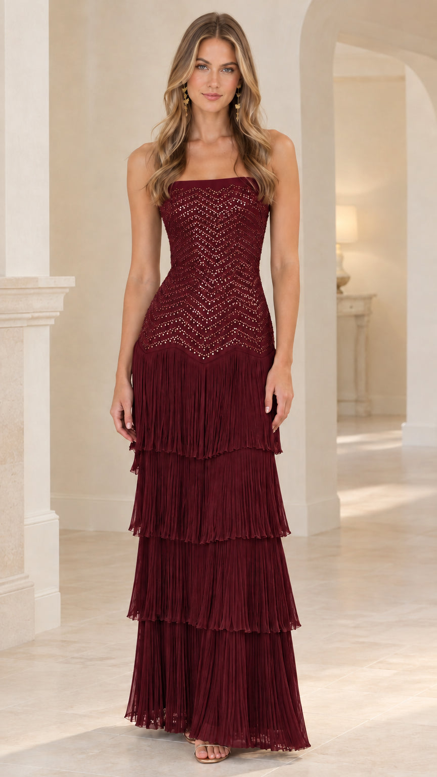 Front view of woman wearing burgundy strapless sequin tiered fringe evening gown