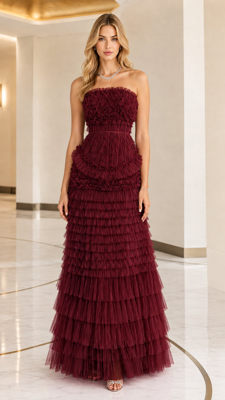 Front full view of woman wearing strapless burgundy tiered ruffle tulle evening gown