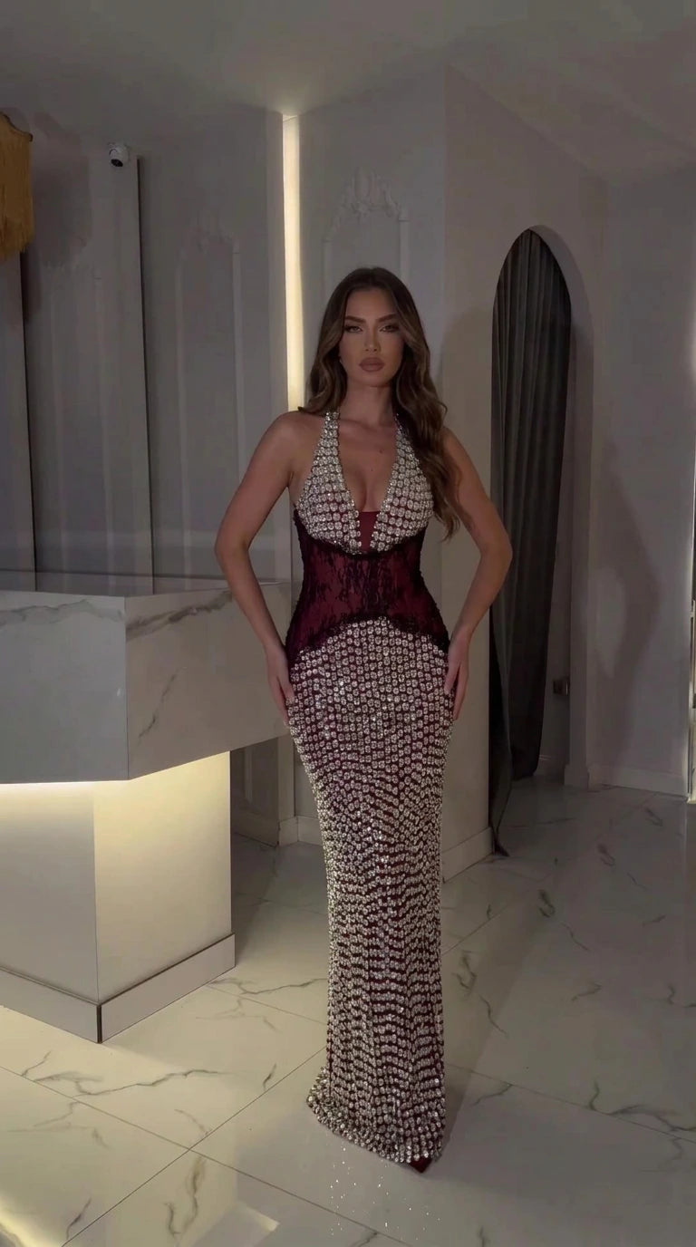 Model wearing burgundy red rhinestone halter maxi dress with corset waist panel