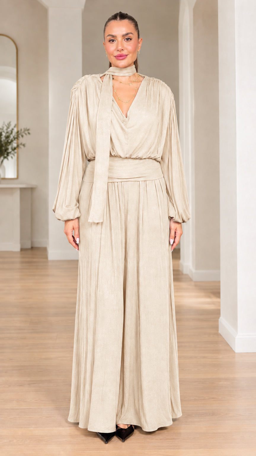 Model wearing champagne beige long-sleeve scarf neck wide-leg jumpsuit